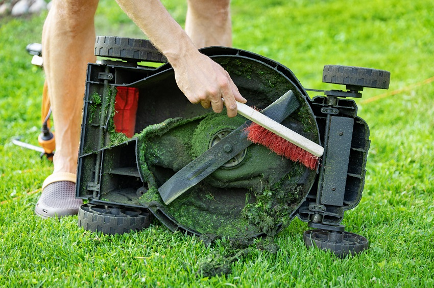 Čištění sekačky od zbytků trávy smetáčkem